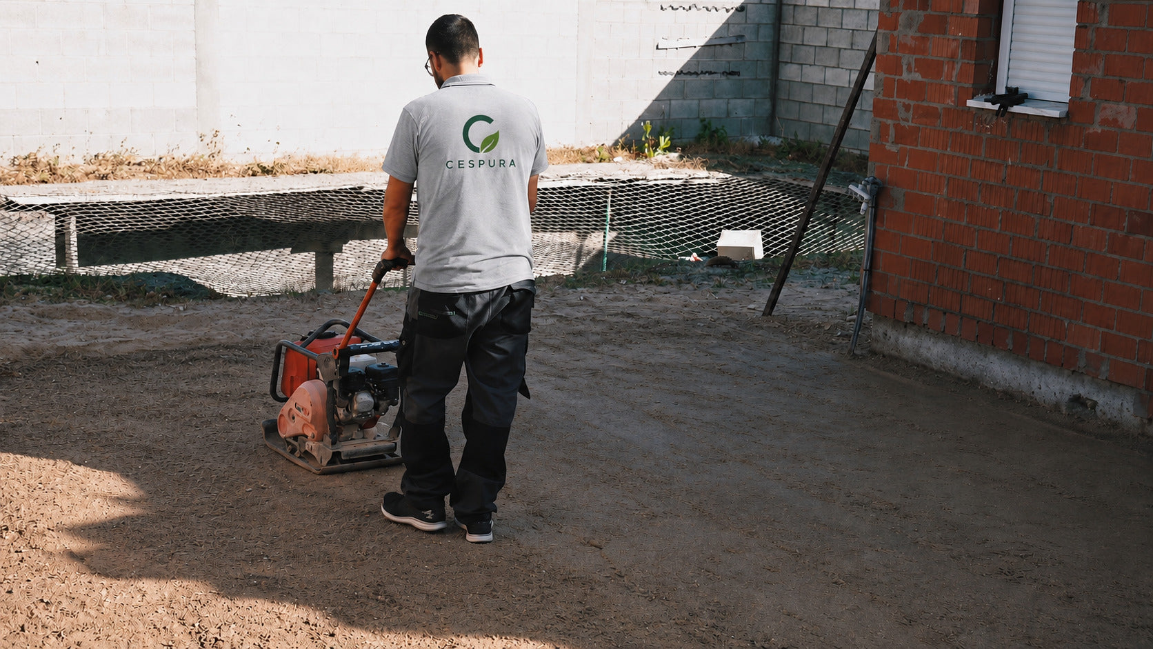 Compactando la tierra antes de instalar el césped artificial